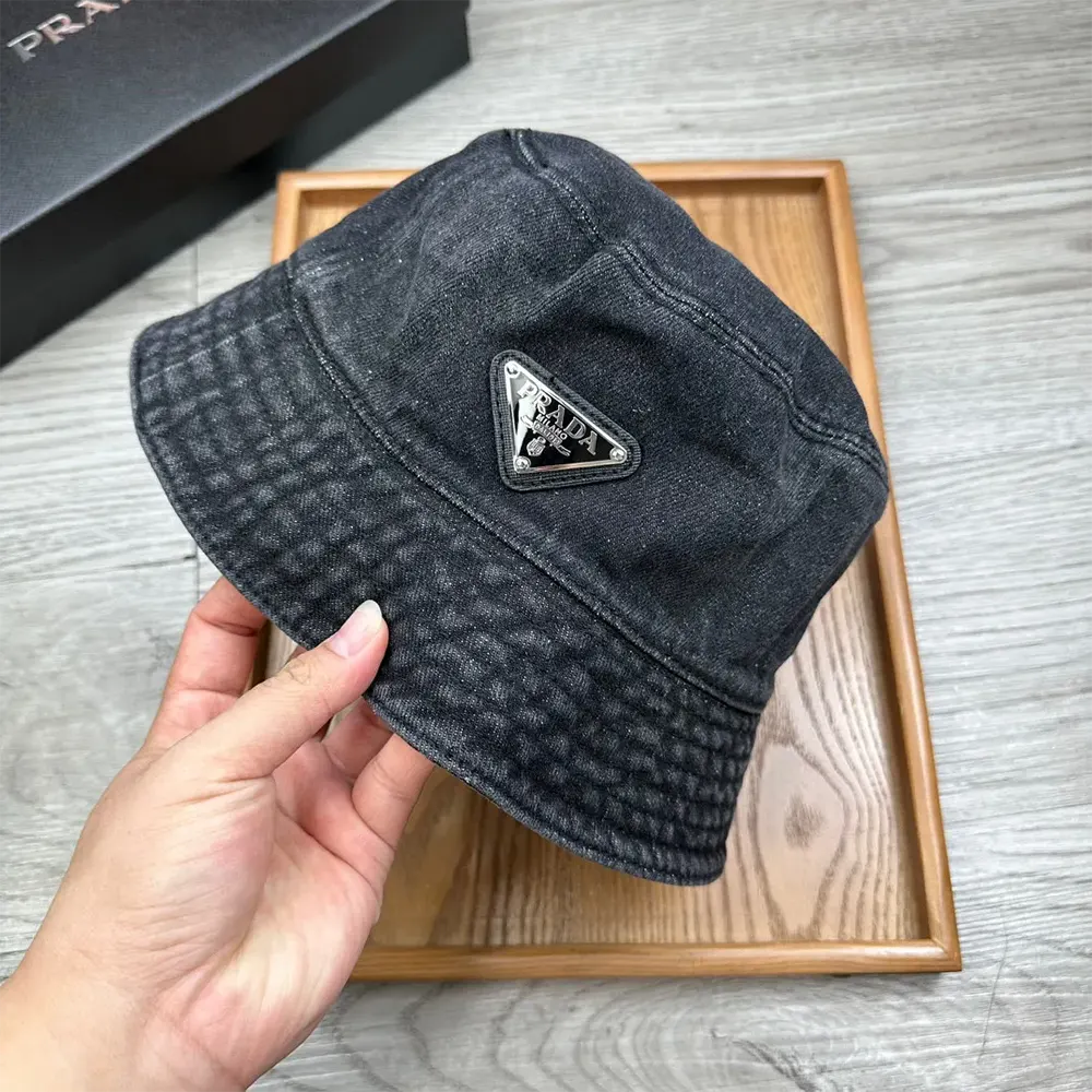 Close-up of black denim texture and metal Prada hardware on bucket hat