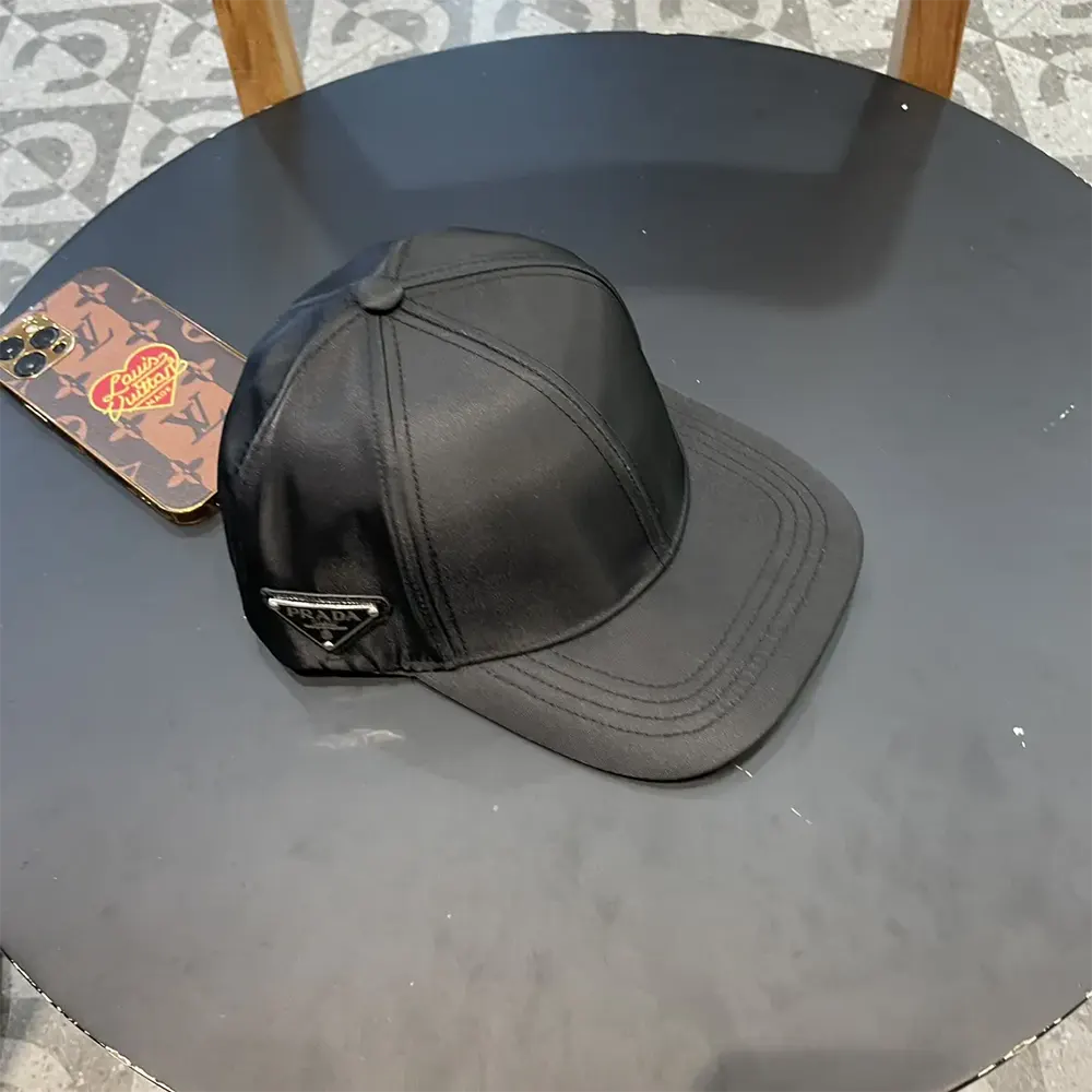 Close-up of Prada logo plaque on black Re-Nylon baseball cap