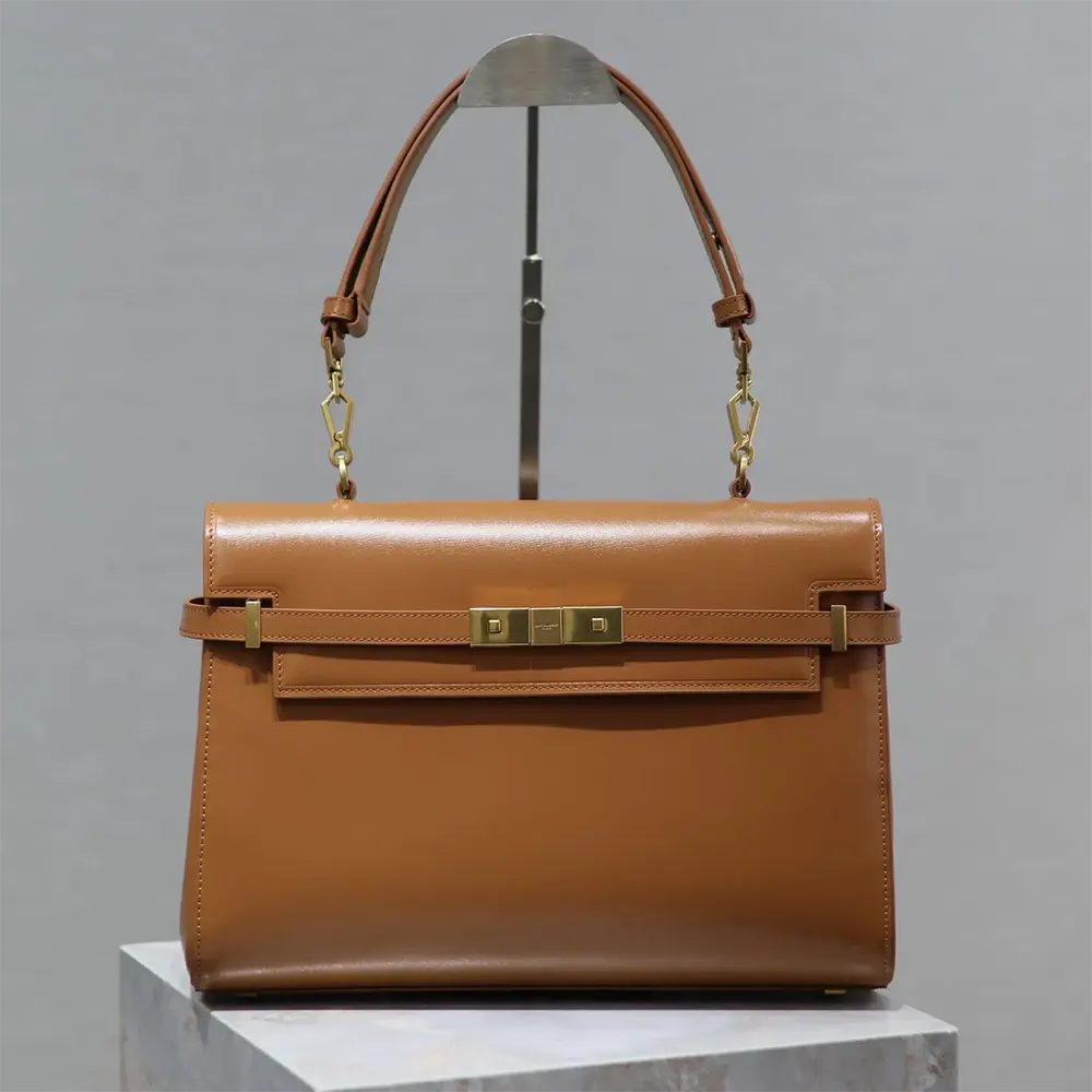 Close-up on gold YSL logo hardware of Manhattan Top-handle brown shoulder bag