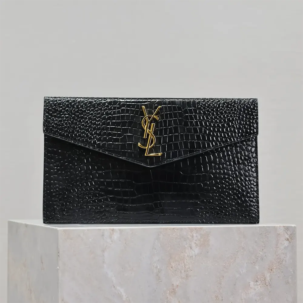 Close-up of gold YSL monogram hardware on Uptown Pouch shiny leather black
