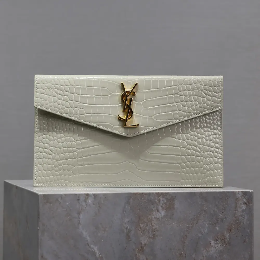 Close-up of gold YSL logo on Uptown Pouch's crocodile-embossed leather