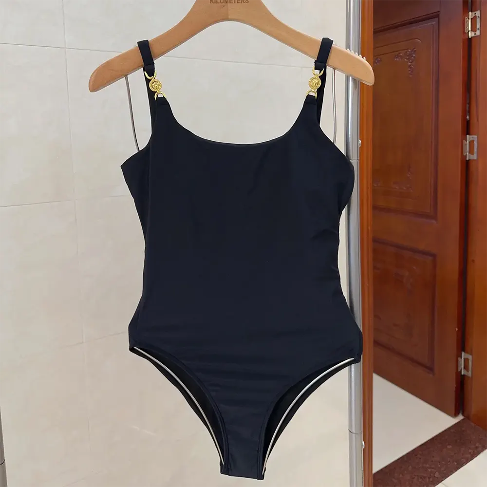 Close-up of gold Medusa emblem detail on swimsuit
