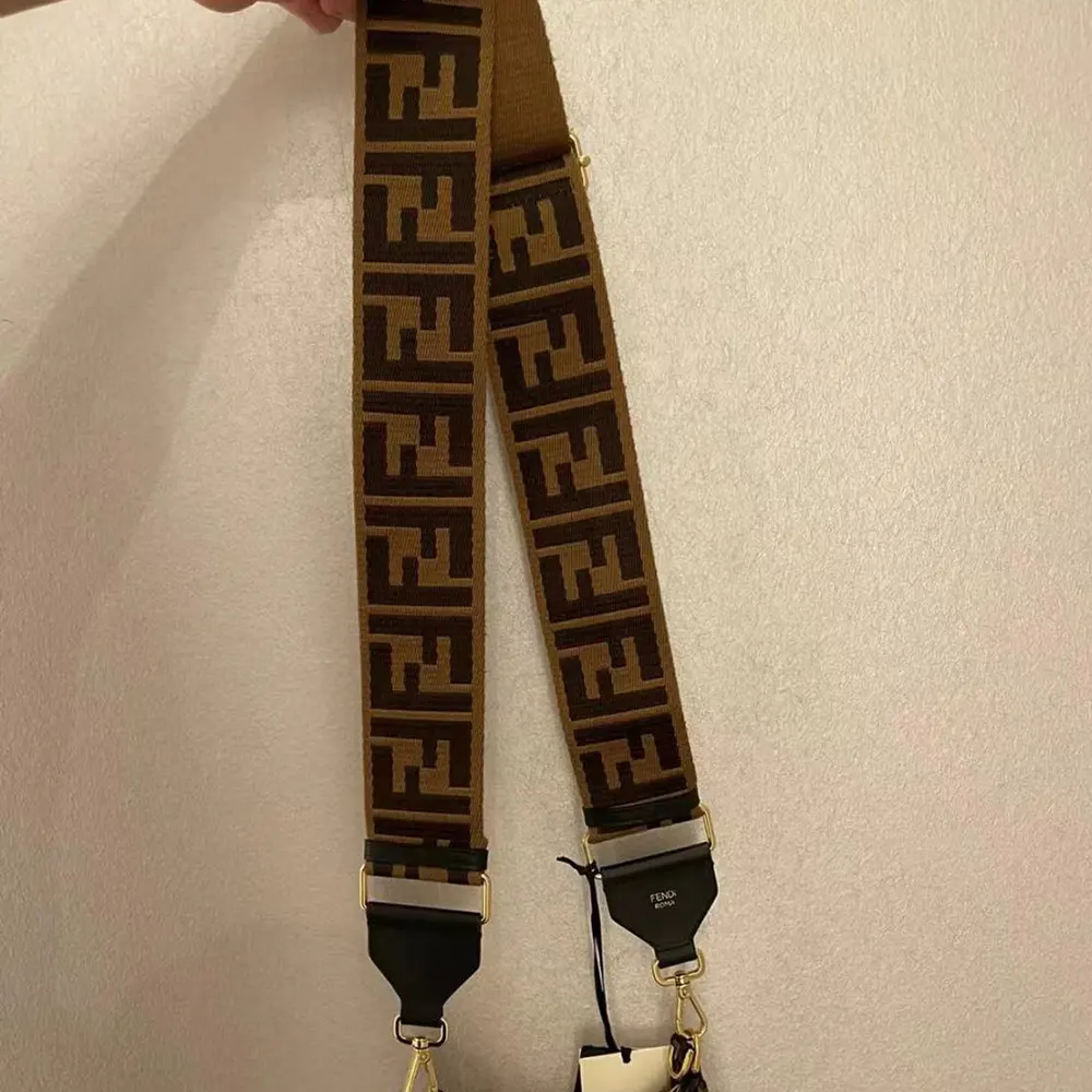 Close-up of gold-tone Fendi logo on brown canvas shoulder strap