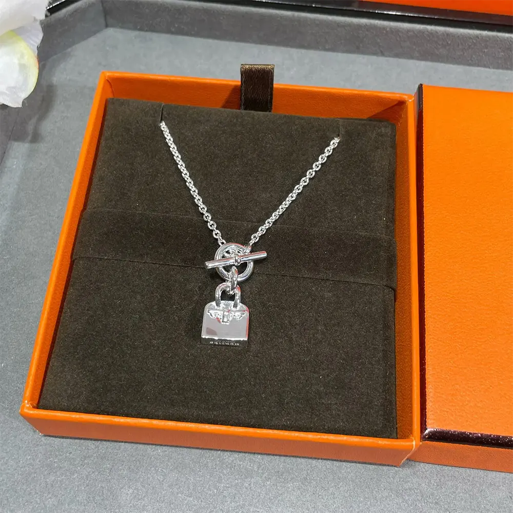 Close-up detail of signature Kelly lock on Hermes pendant