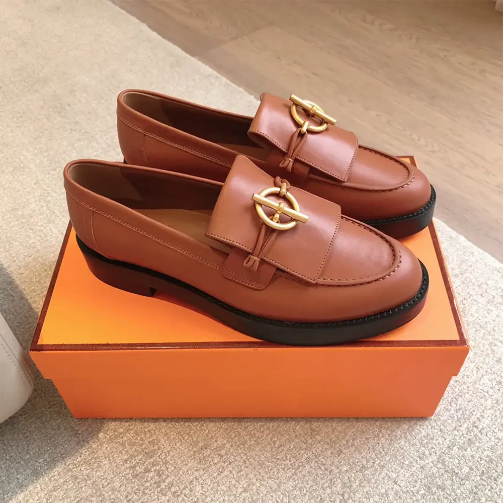 Close-up of Hermes emblem hardware on brown Impact Loafer