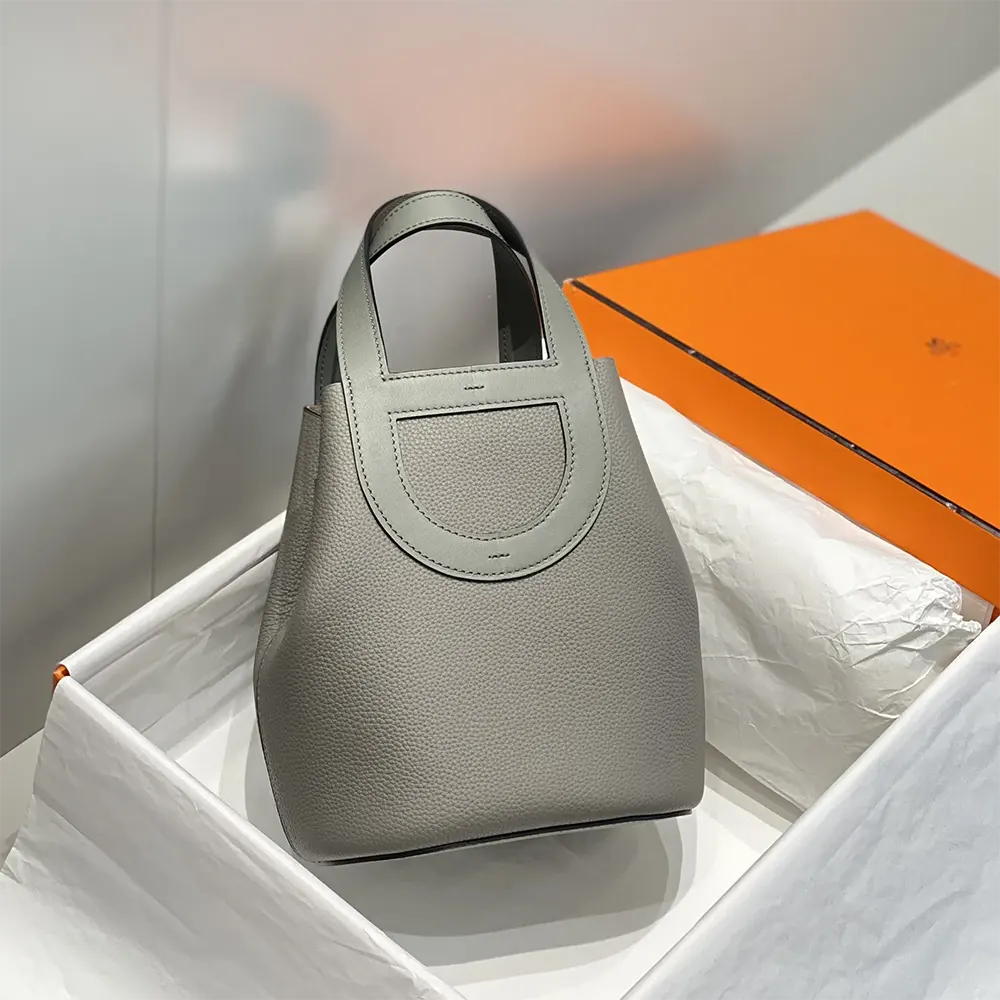 Close-up of gold hardware and gray Clemence leather texture handbag