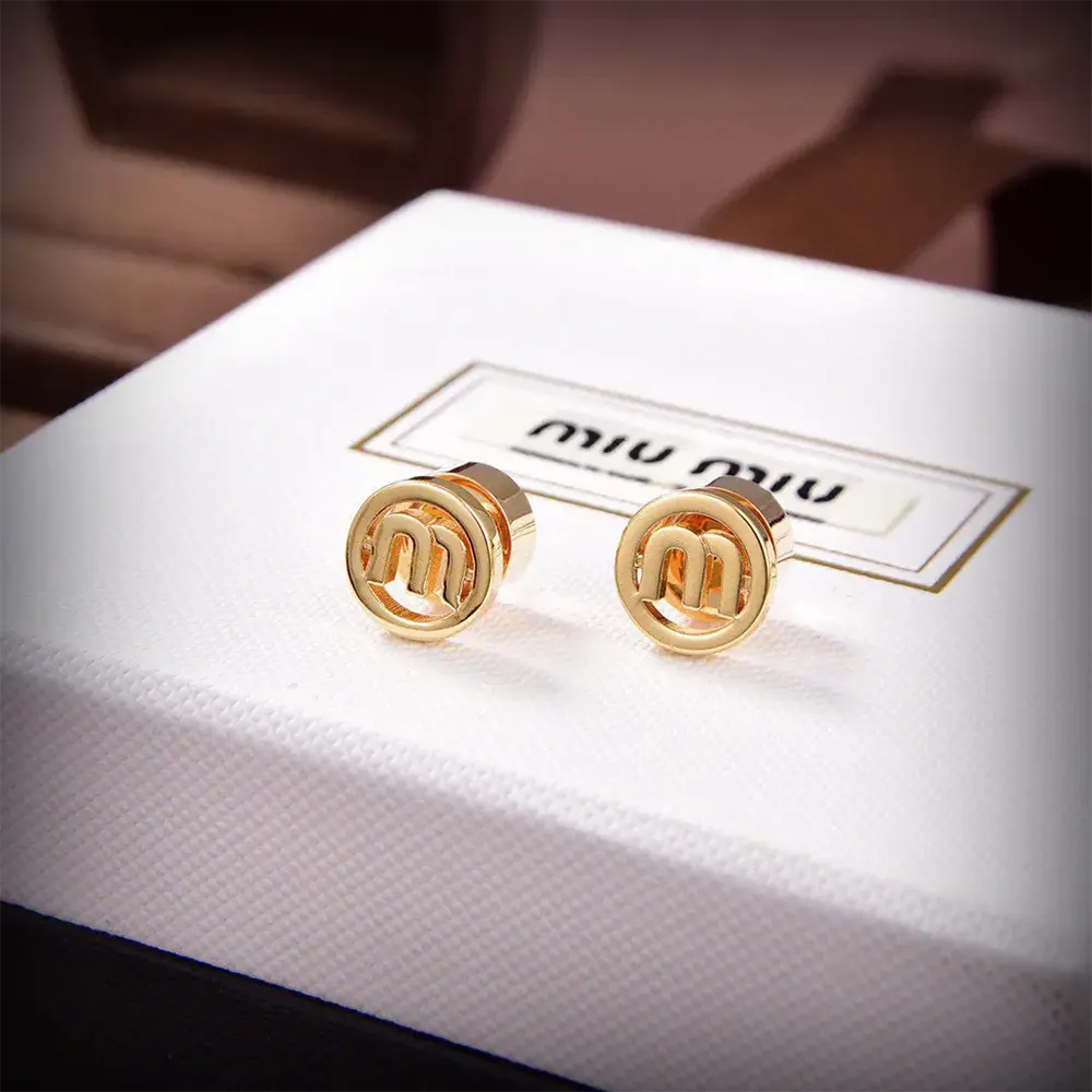 Styled shot of Miu Miu Women Metal Earrings with gold reflective surface