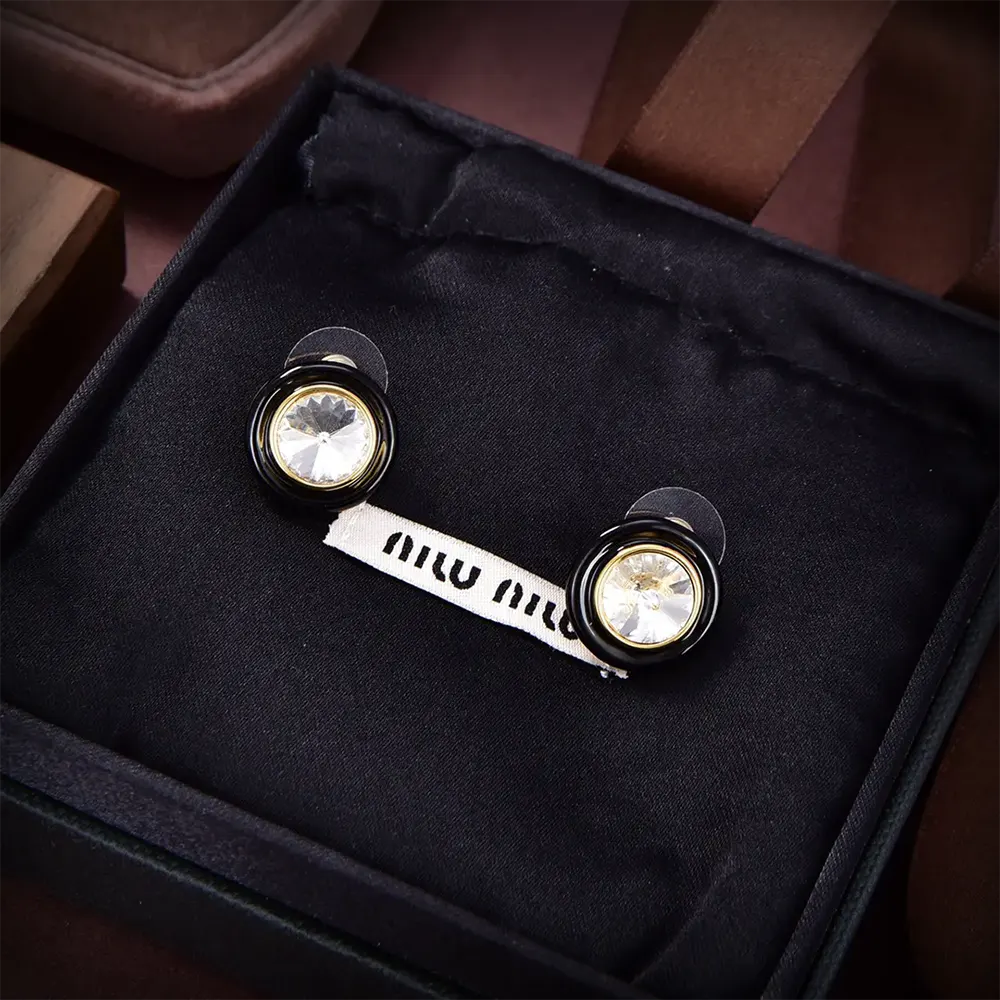 Close-up detail of polished metal and black Plexiglas on Miu Miu earrings