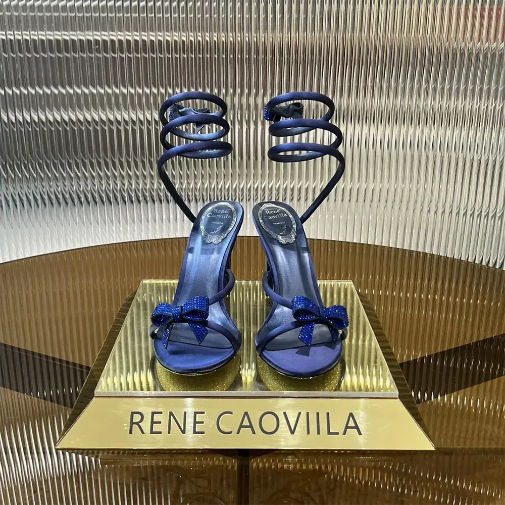 Close-up of navy satin bow and gold buckle on Rene Caovilla sandal