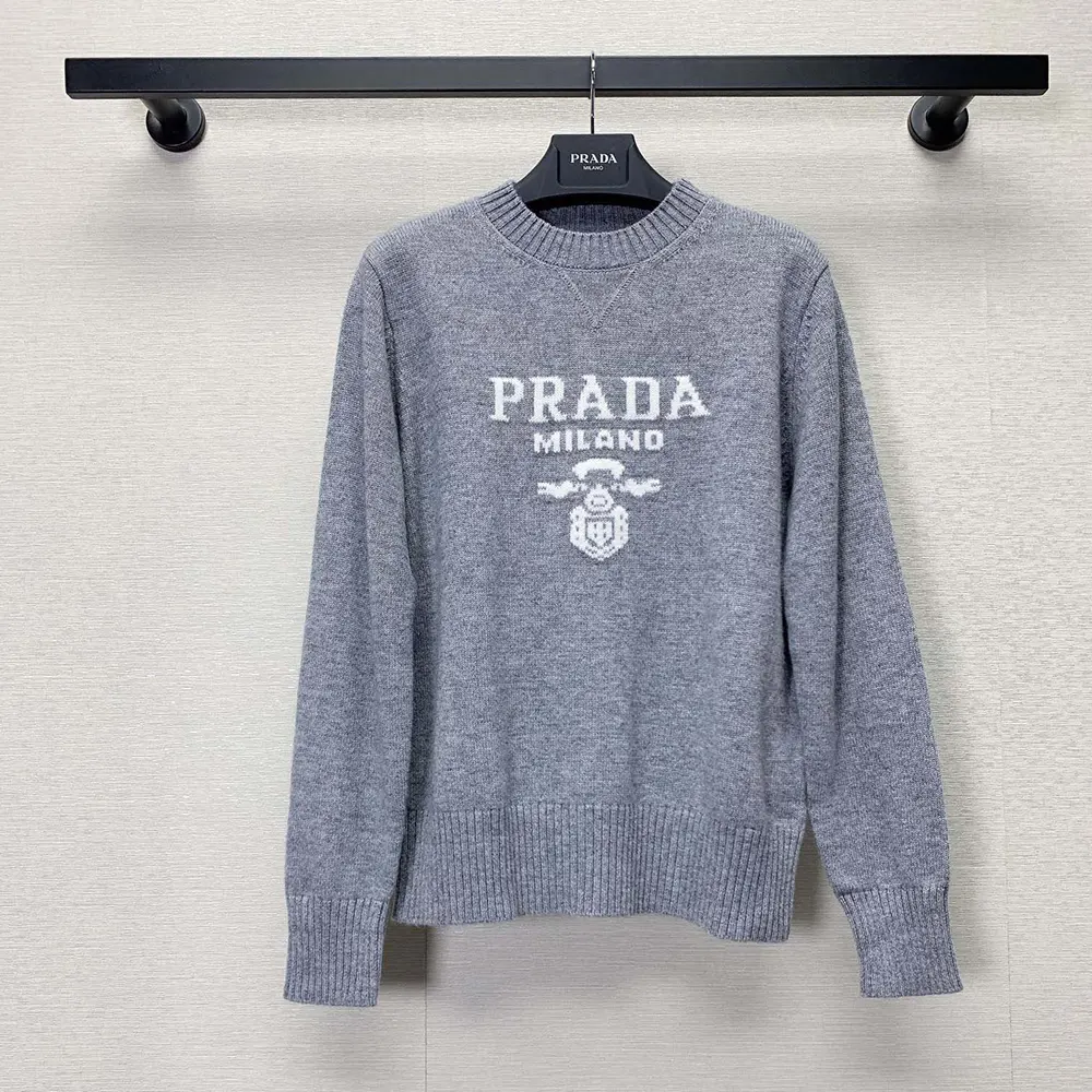 Close-up of silver fabric texture and Prada logo detail on sweater
