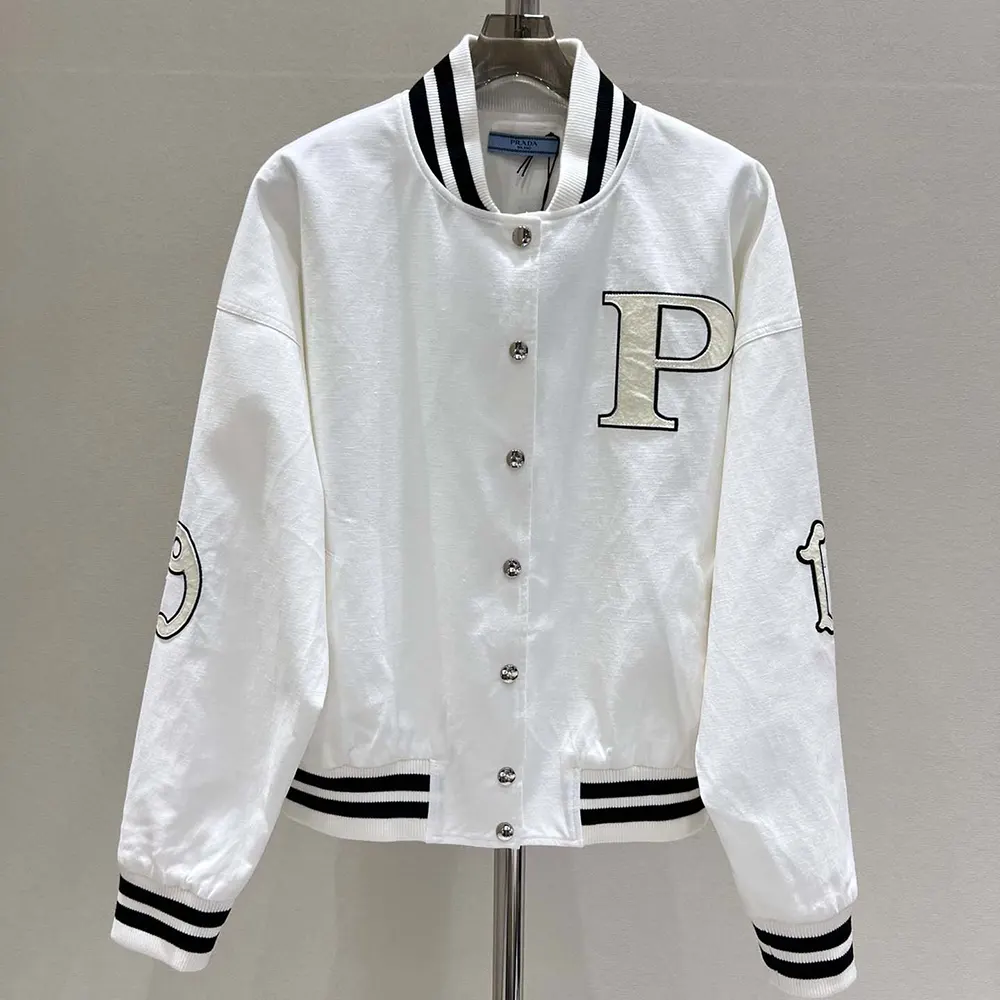Close-up of embroidered patches and branded hardware on Prada bomber jacket