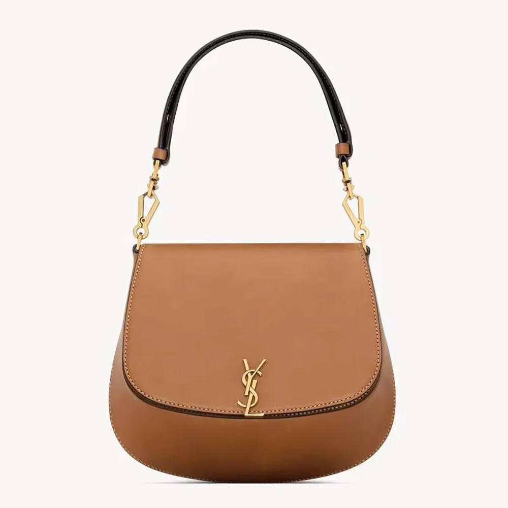 Close-up of gold-tone YSL logo on black box leather bag