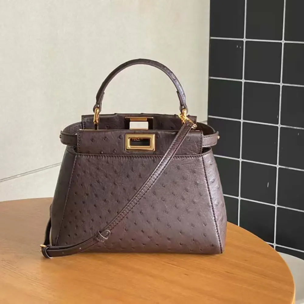 Close-up of bordeaux ostrich leather texture and gold hardware detail