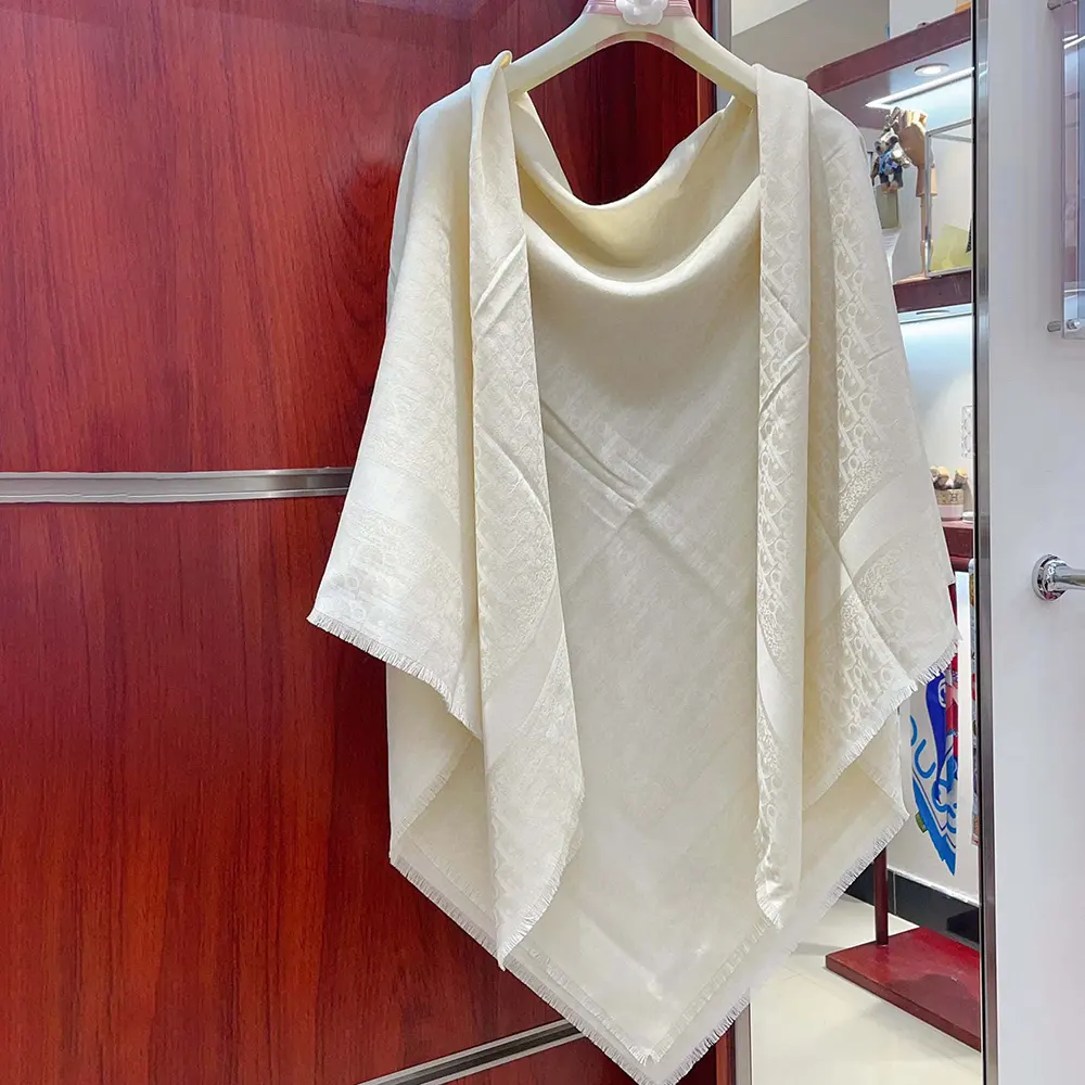 Close-up of signature Dior oblique pattern on white shawl