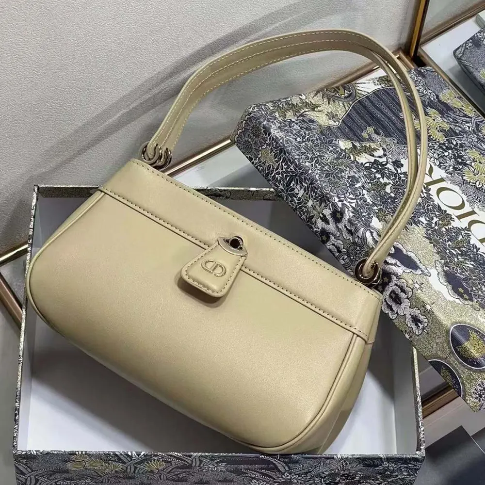 Close-up detail of sandy box calfskin texture and 'D' closure on Dior Key Bag