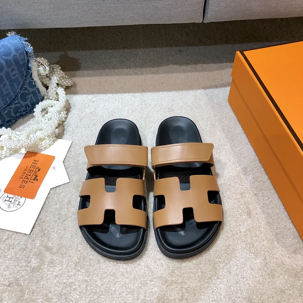 Close-up of embossed Hermes detail on brown leather sandal