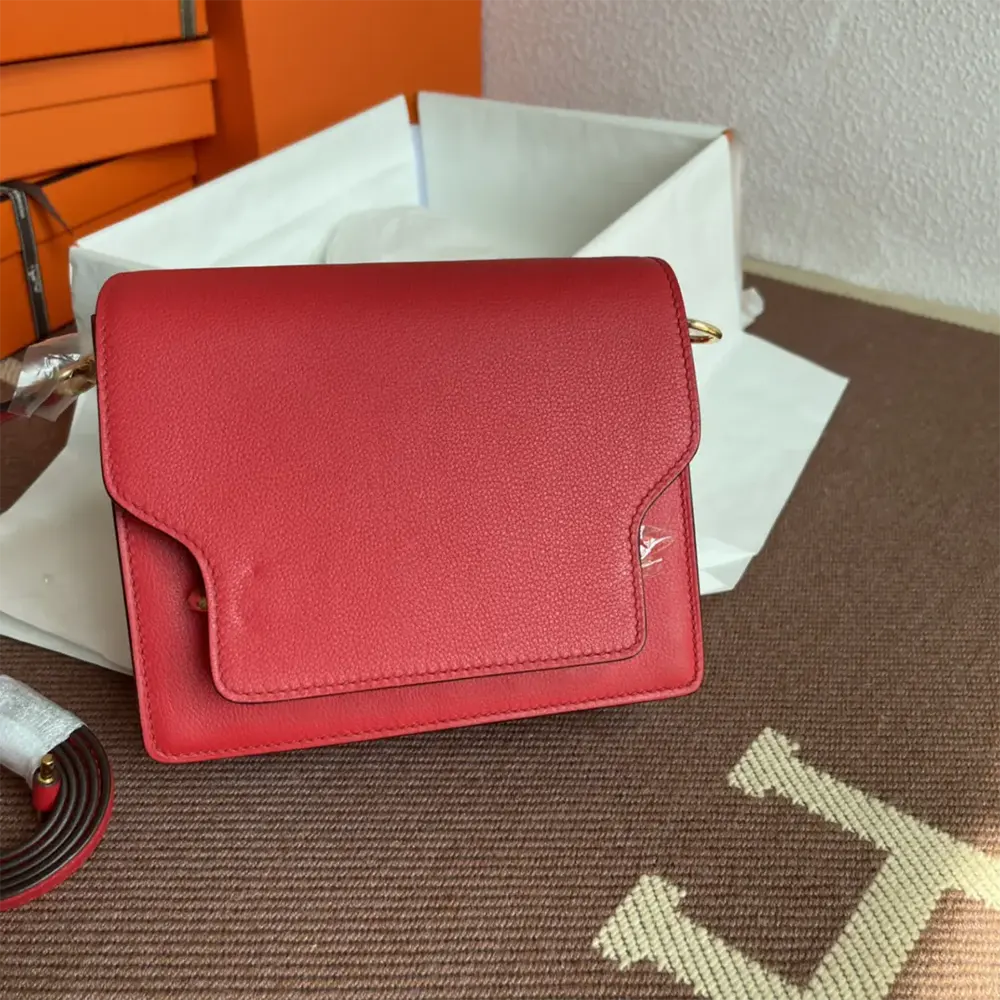 Side angle showing slim silhouette of Hermes Women Roulis Mini Bag in red