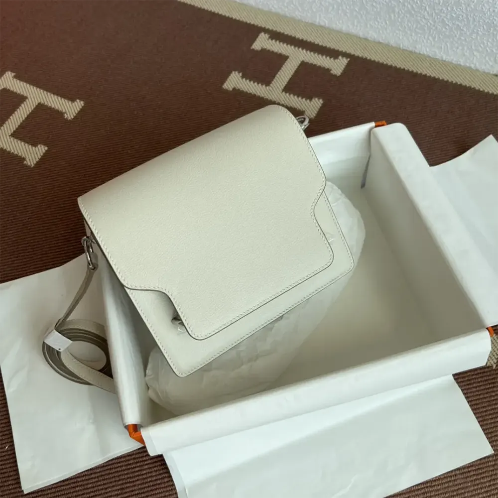 Side angle showing compact silhouette of Hermes Women Roulis Mini Bag white