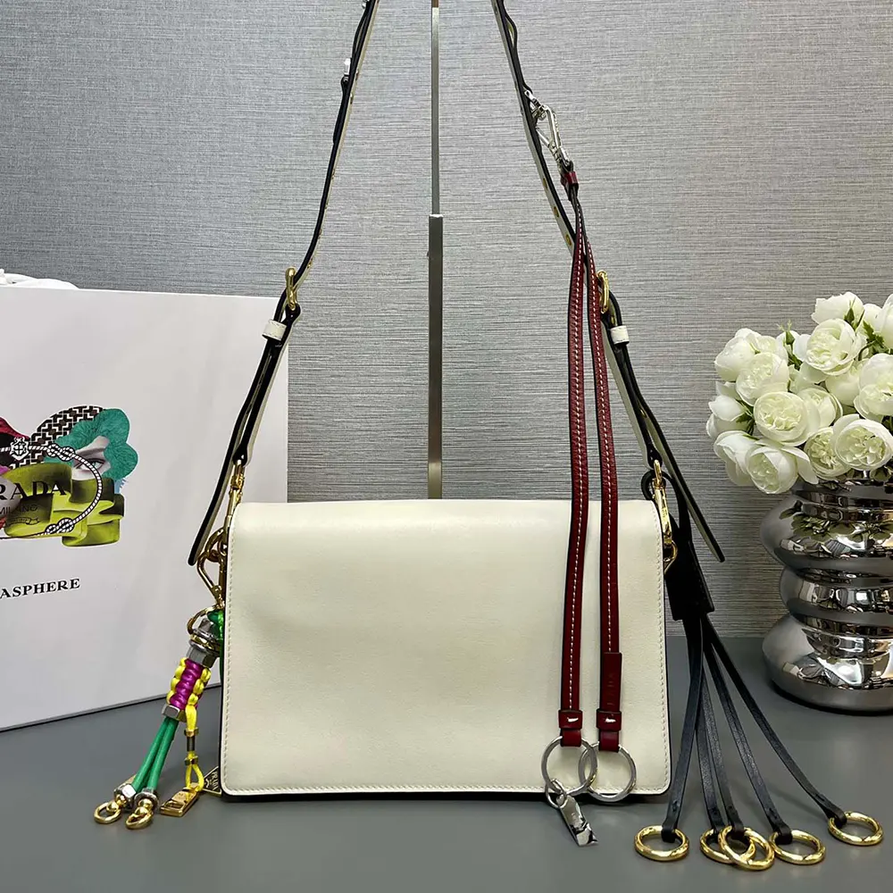 Side angle showing compact silhouette of Prada Women Soft Sound Small Leather Shoulder Bag with Charms-White