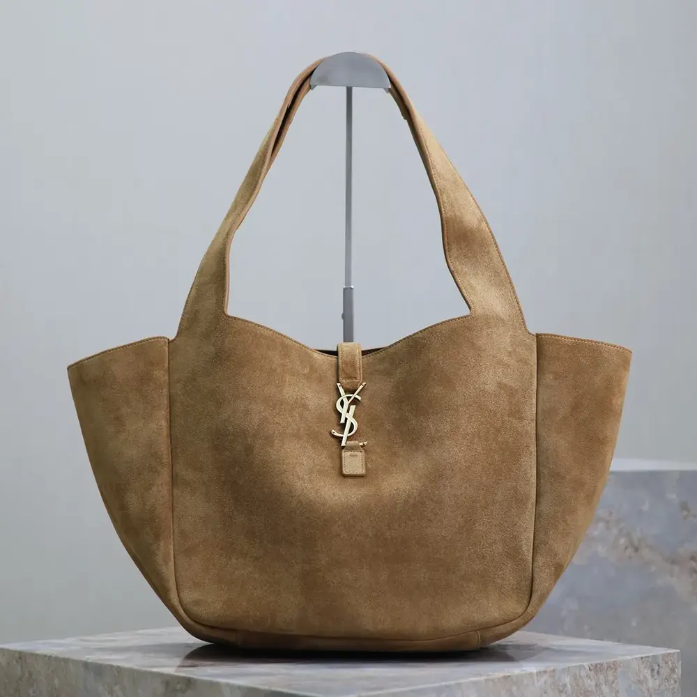 Close-up of gold YSL logo hardware on brown suede bag