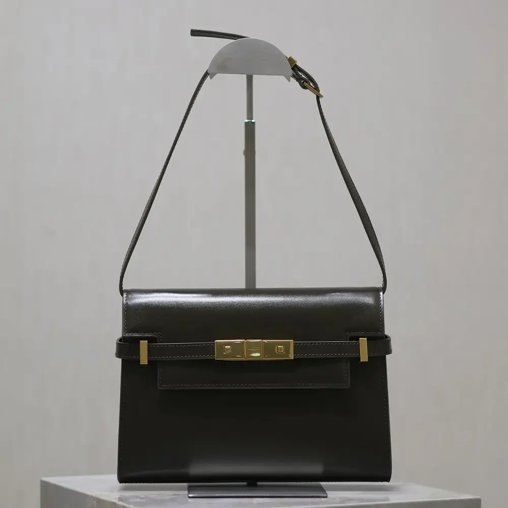 Close-up of gold YSL logo on dark green box leather bag