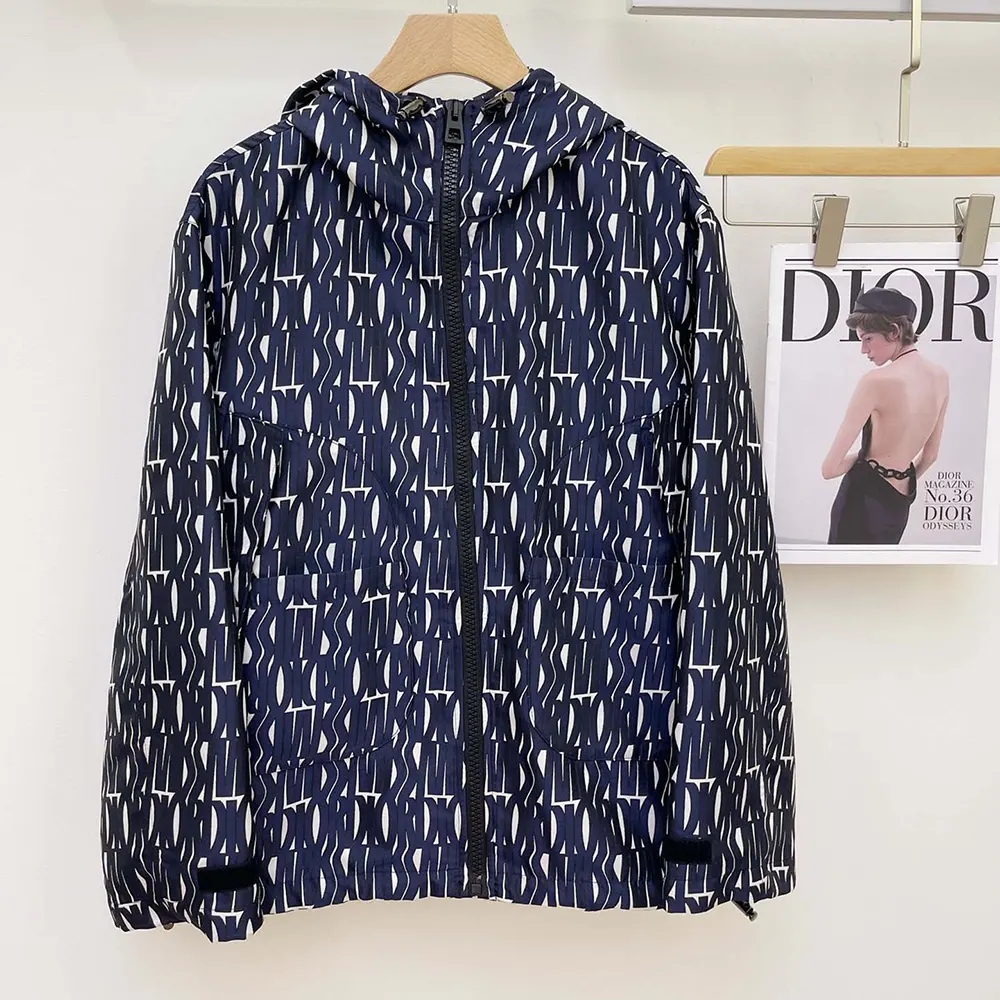 Close-up of embossed Dior hardware on navy hooded jacket