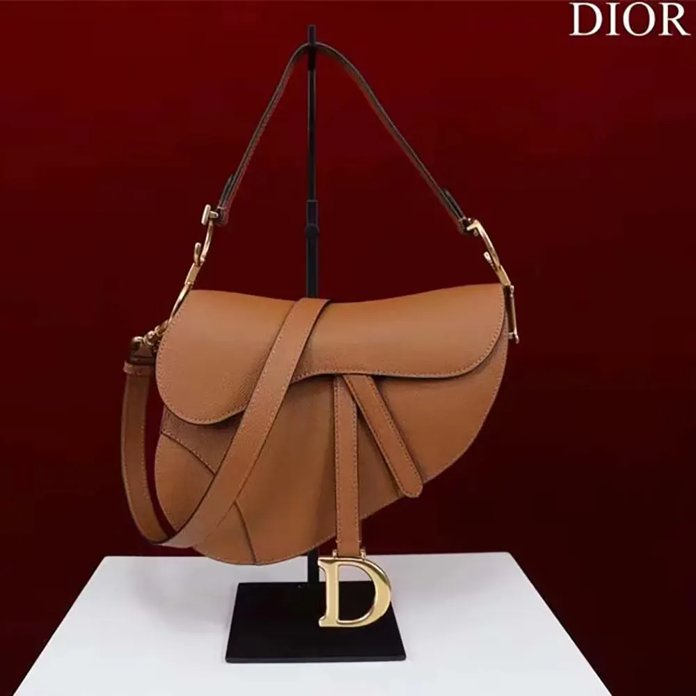 Close-up of golden 'CD' hardware on Dior Women CD Saddle Bag Strap