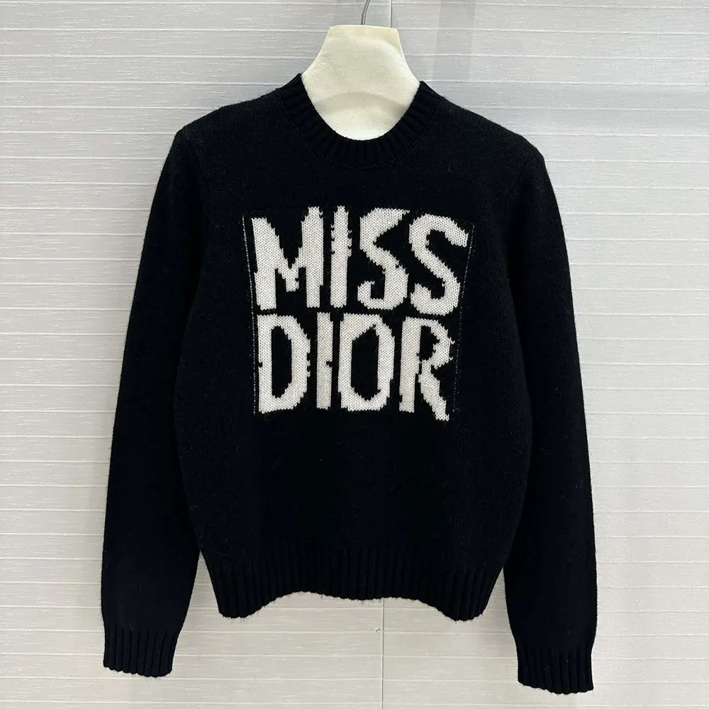 Close-up of white Miss Dior graffiti detail on black cashmere and silk knit sweater