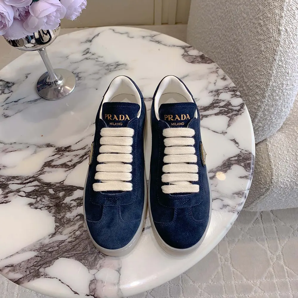 Close-up detail of Hermes embossed logo on Prada Unisex Suede Sneakers heel