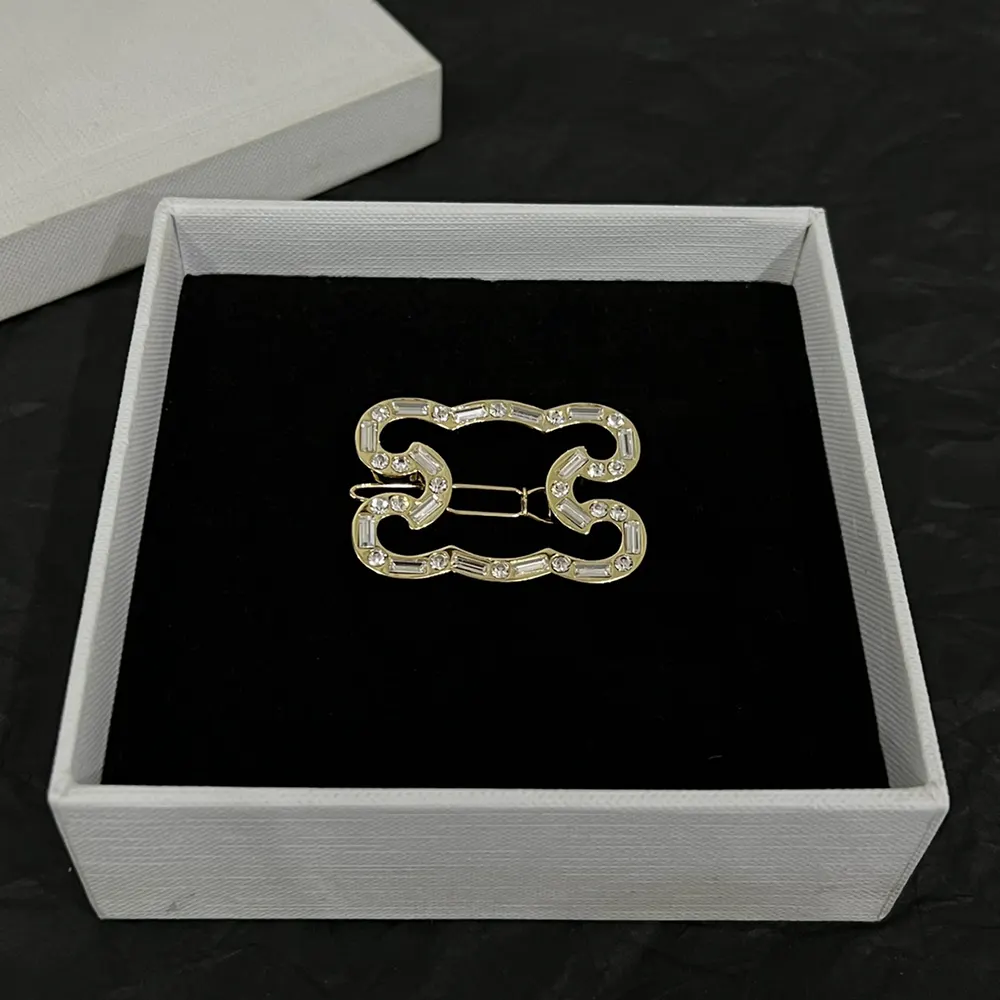 Celine Women Triomphe Frame Sparkle Brooch pinned on a gold-tone fabric background