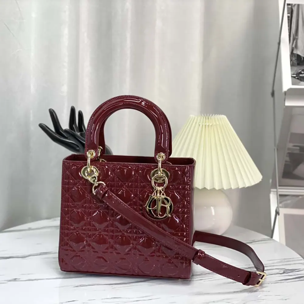 Close-up detail of gold D.I.O.R. charms on Lady Dior Bag in cherry red