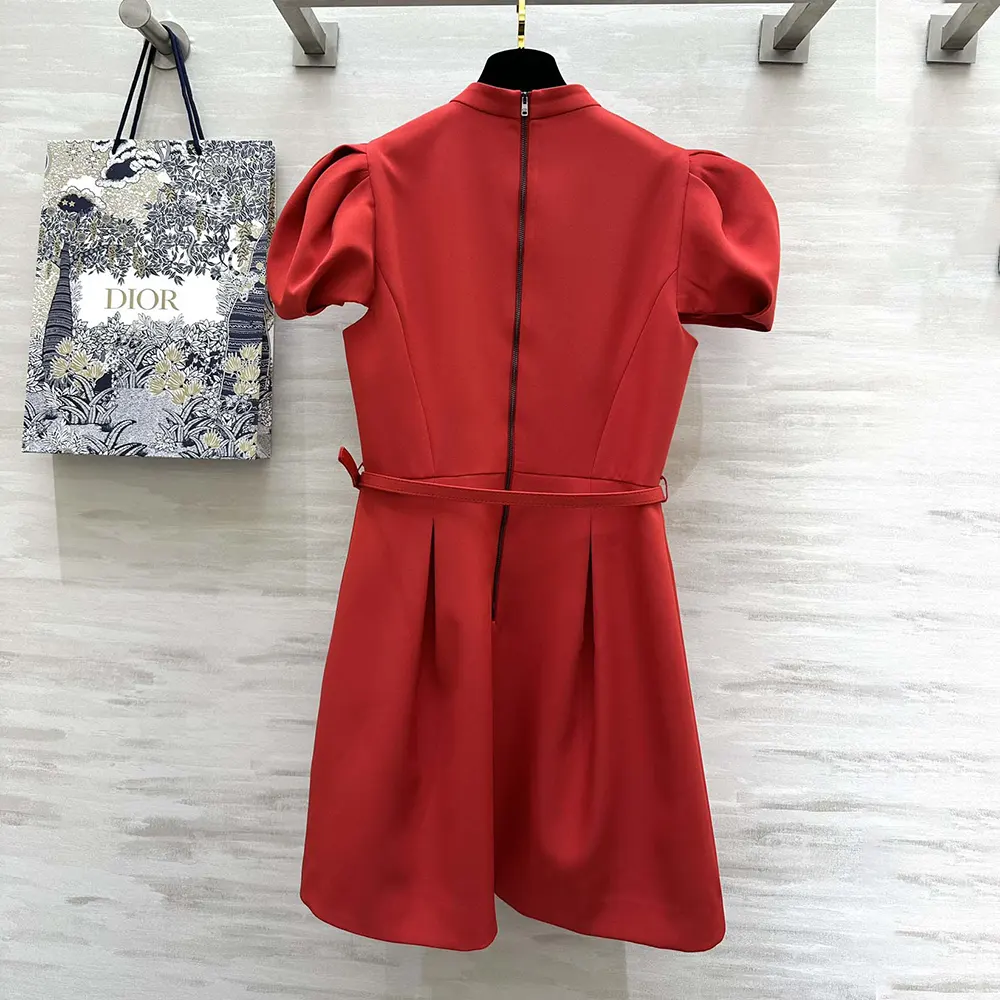 Close-up detail of Dior signature belt on bright red dress