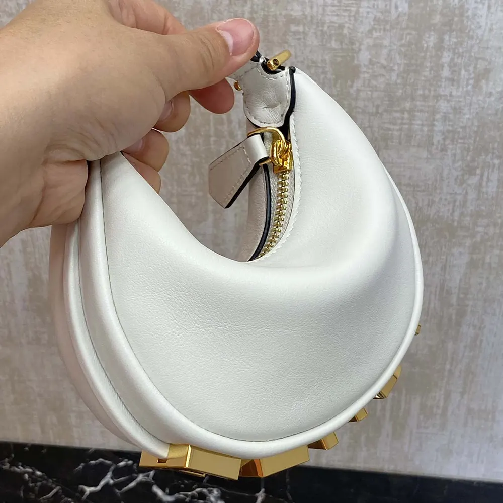 Close-up of gold Fendigraphy logo hardware on white leather bag