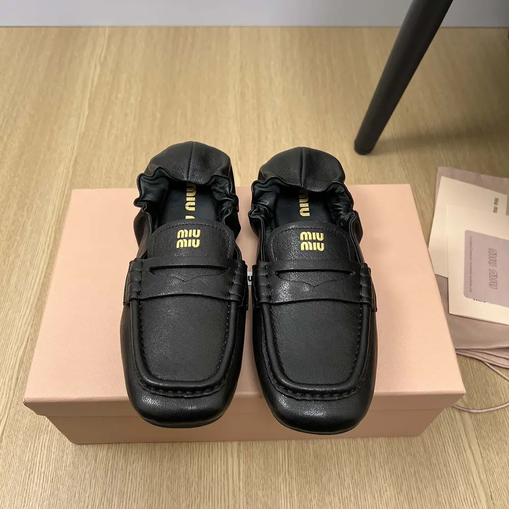 Close-up of black nappa leather and metal logo on Miu Miu loafers