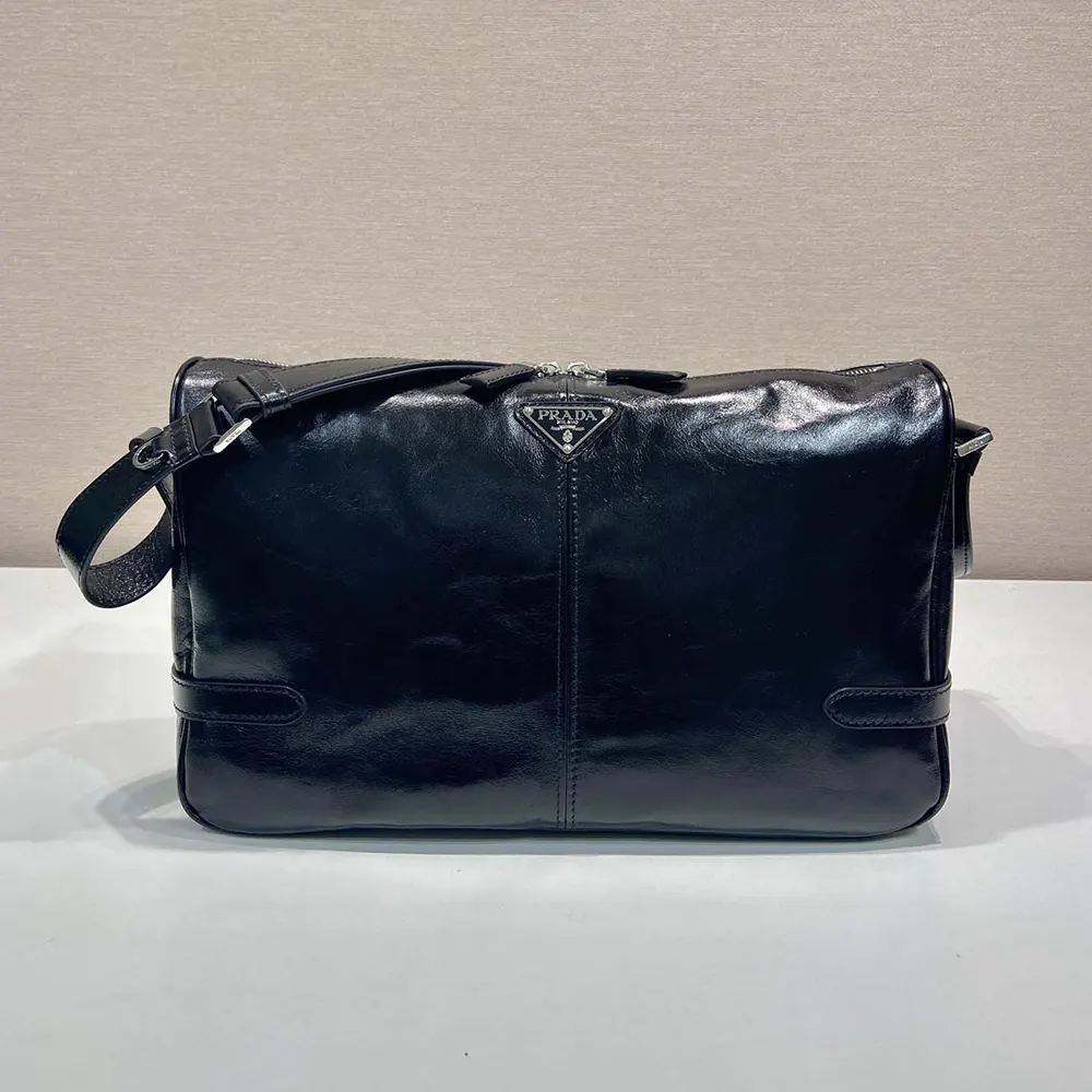 Close-up of smooth black leather and signature Prada plaque on shoulder bag