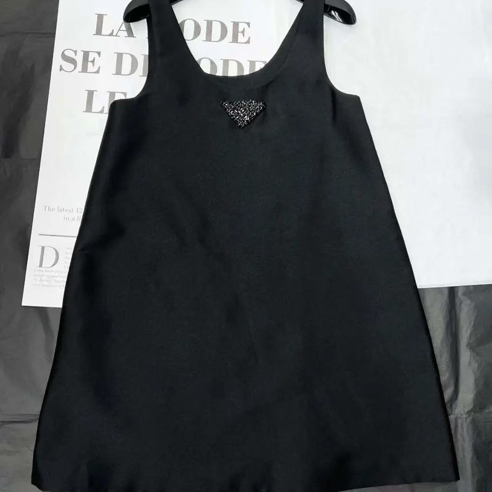 Close-up of black metal triangle logo on Prada Re-Nylon mini-dress