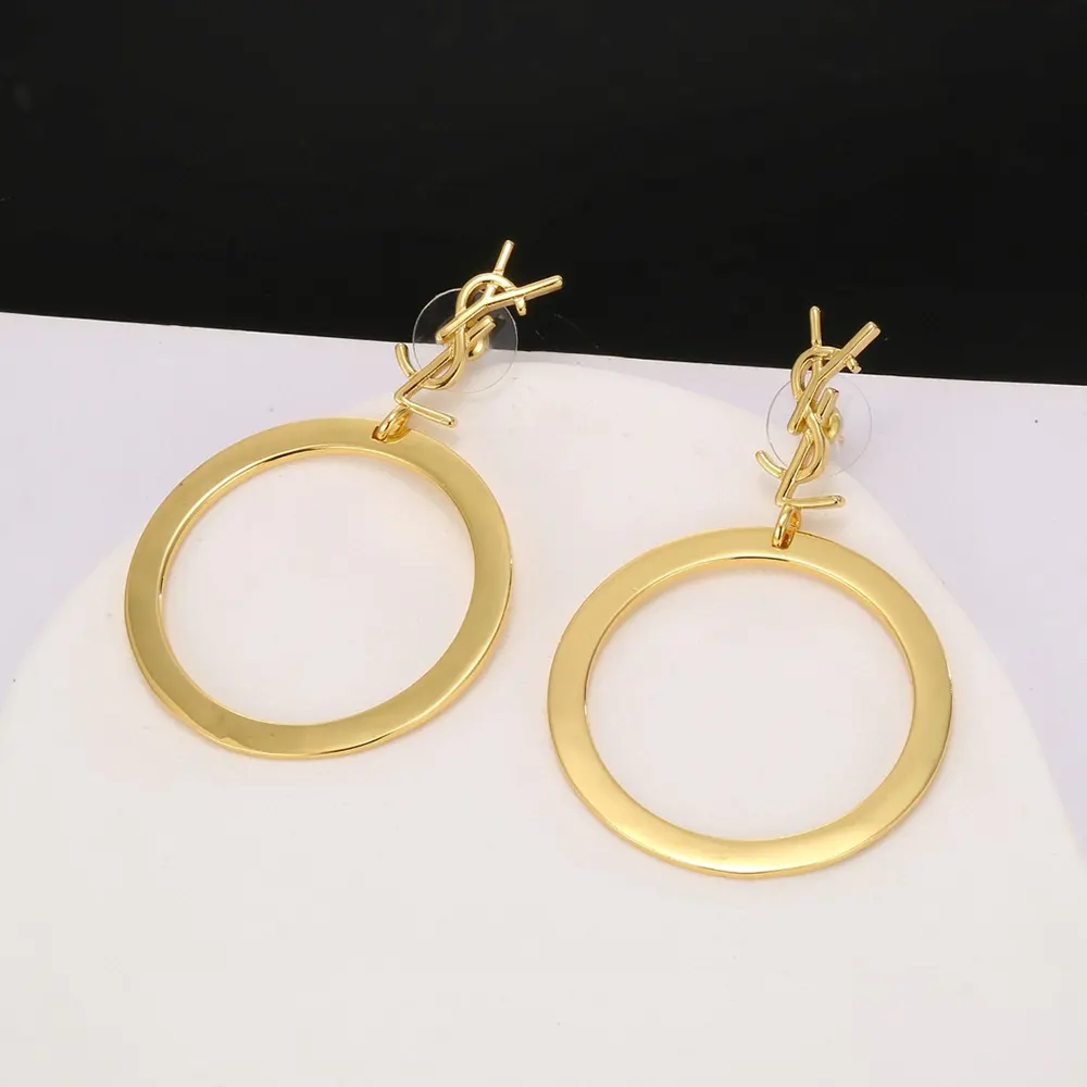 Close-up on signature YSL pendant detail of Cassandre pendant hoop earrings