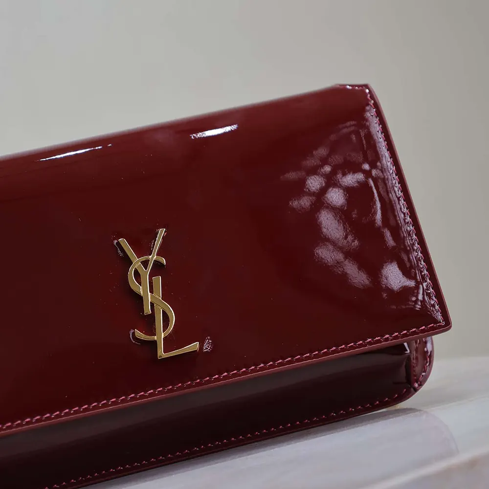 Close-up of gold YSL logo hardware on patent leather phone holder
