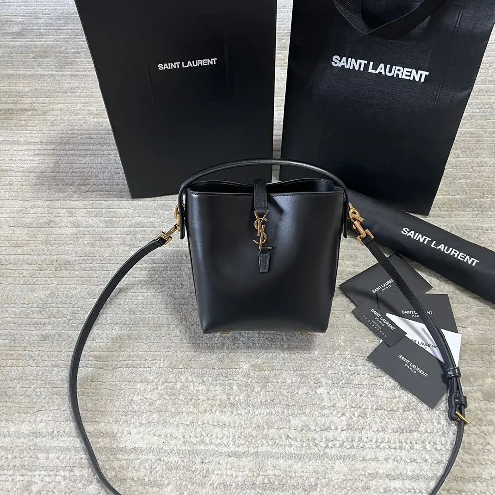 Close-up of gold YSL logo on shiny black leather bag