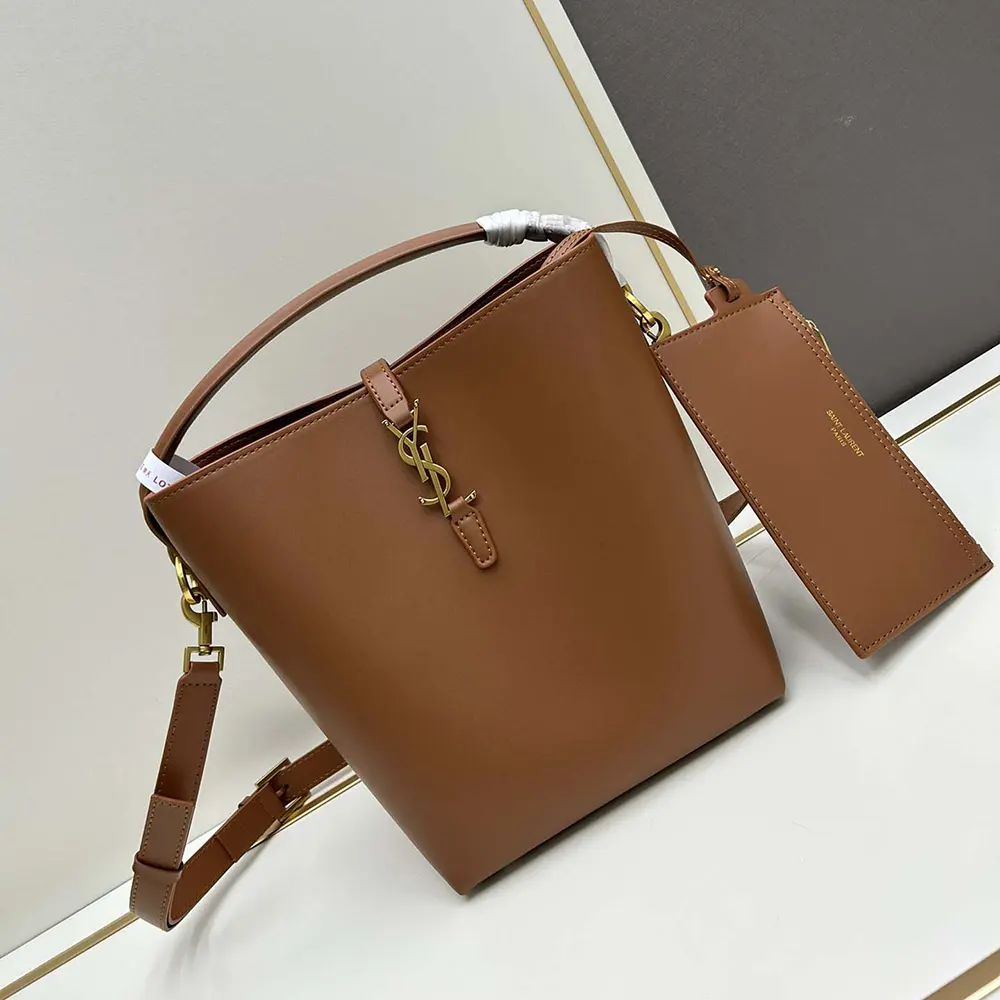 Close-up of gold YSL logo on shiny leather brown Saint Laurent bag