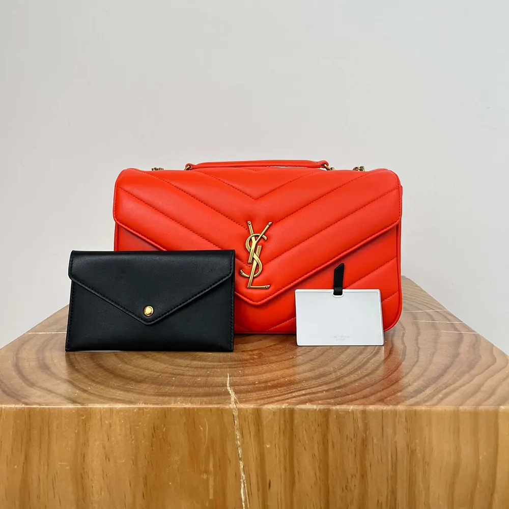 Close-up of gold YSL hardware on orange Loulou Medium bag
