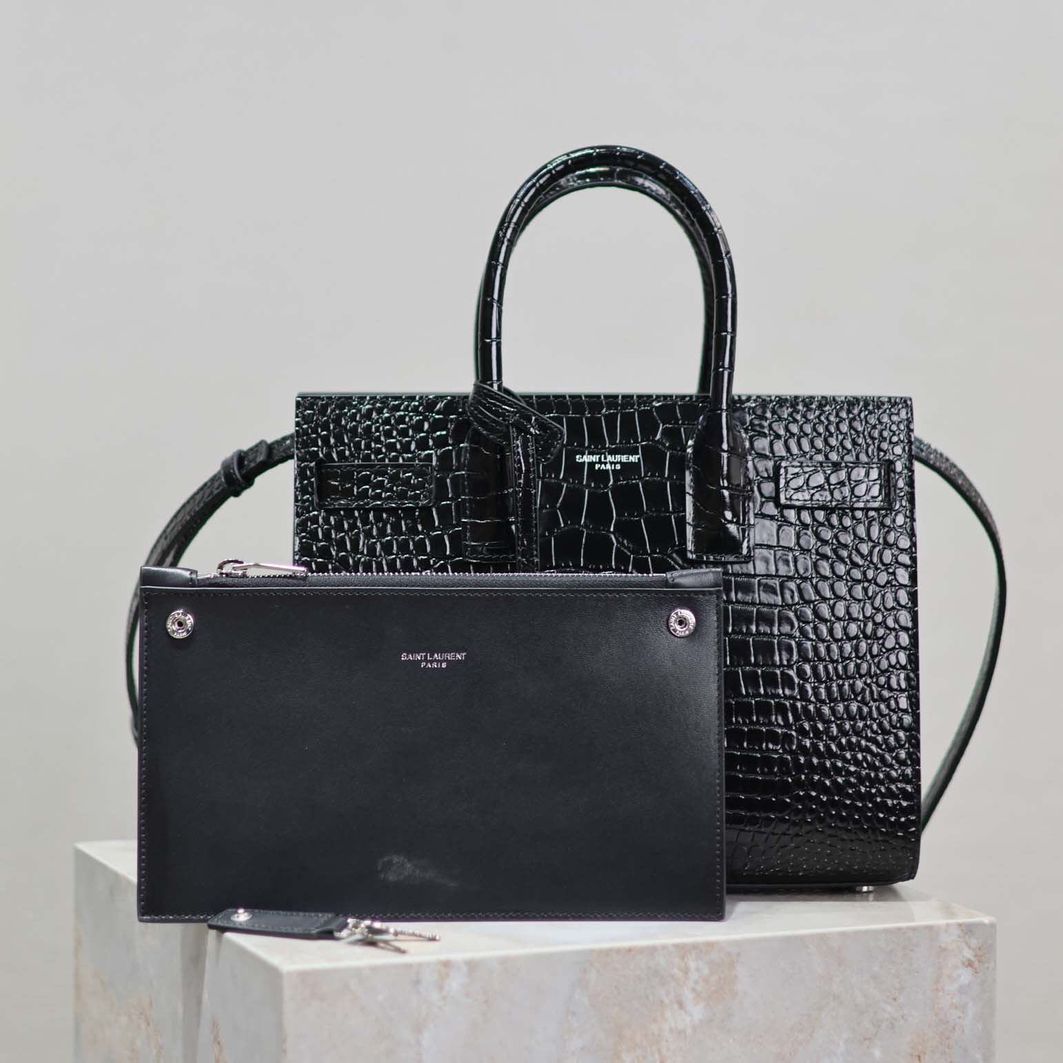 Close-up of signature YSL hardware on embossed crocodile leather bag