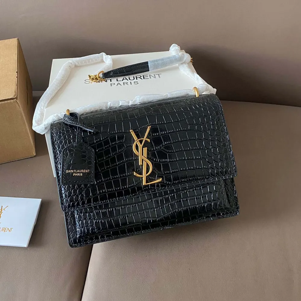 Close-up of gold YSL hardware on black crocodile-embossed leather bag