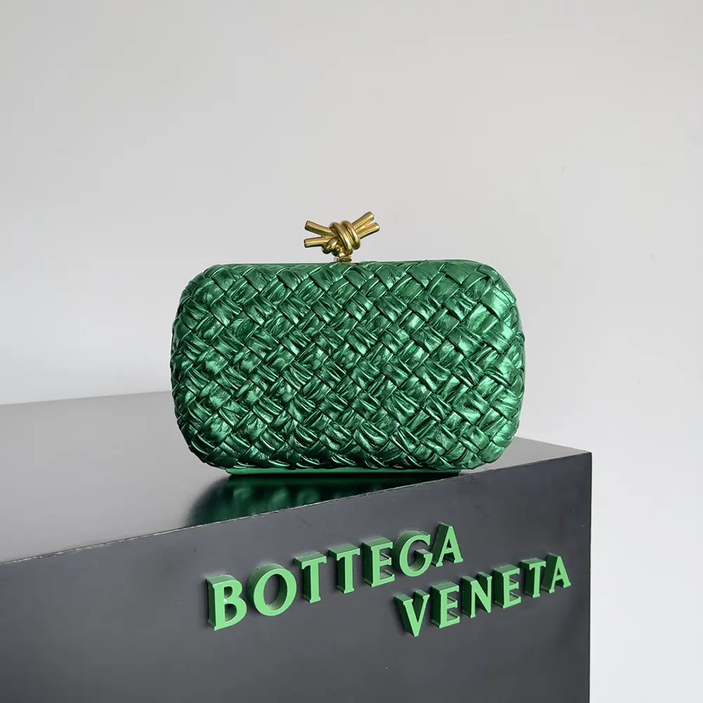 Close-up of signature gold-tone knot clasp on green leather clutch