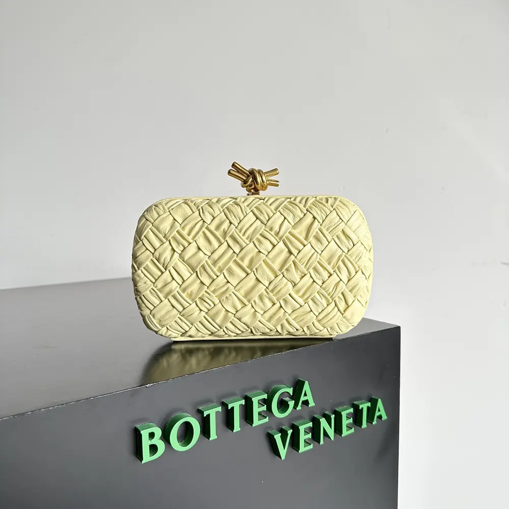 Close-up of signature gold-tone knot closure on yellow Bottega Veneta clutch