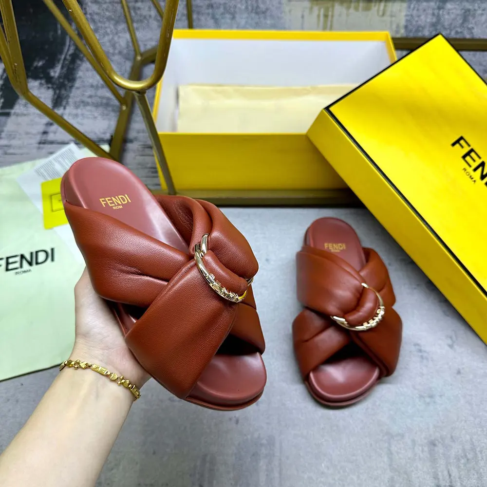Close-up of gold Fendi logo hardware on maroon leather slides