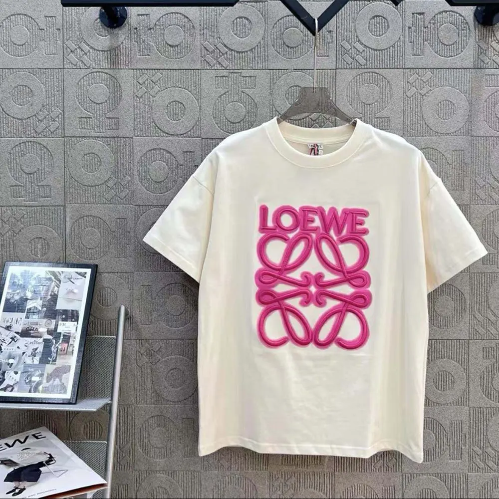 Close-up detail of neon pink Loewe logo on white T-shirt