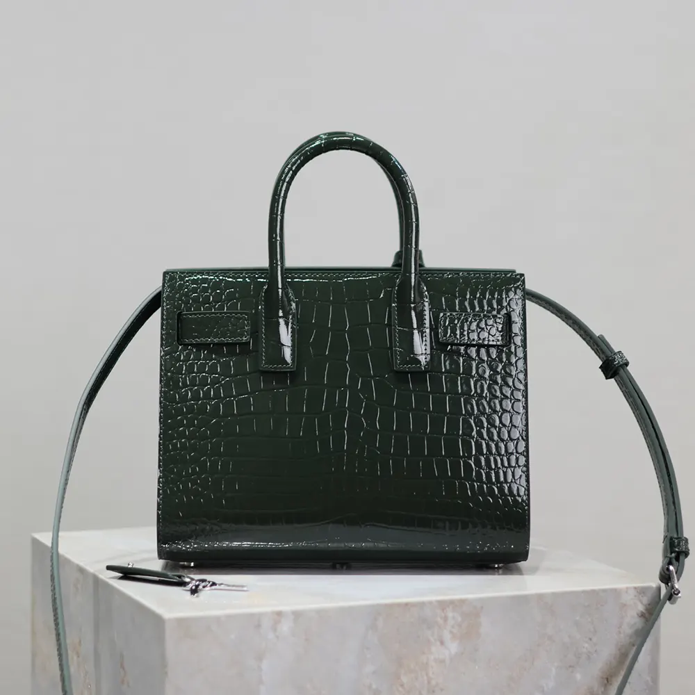 Close-up of gold YSL logo hardware on crocodile embossed leather bag