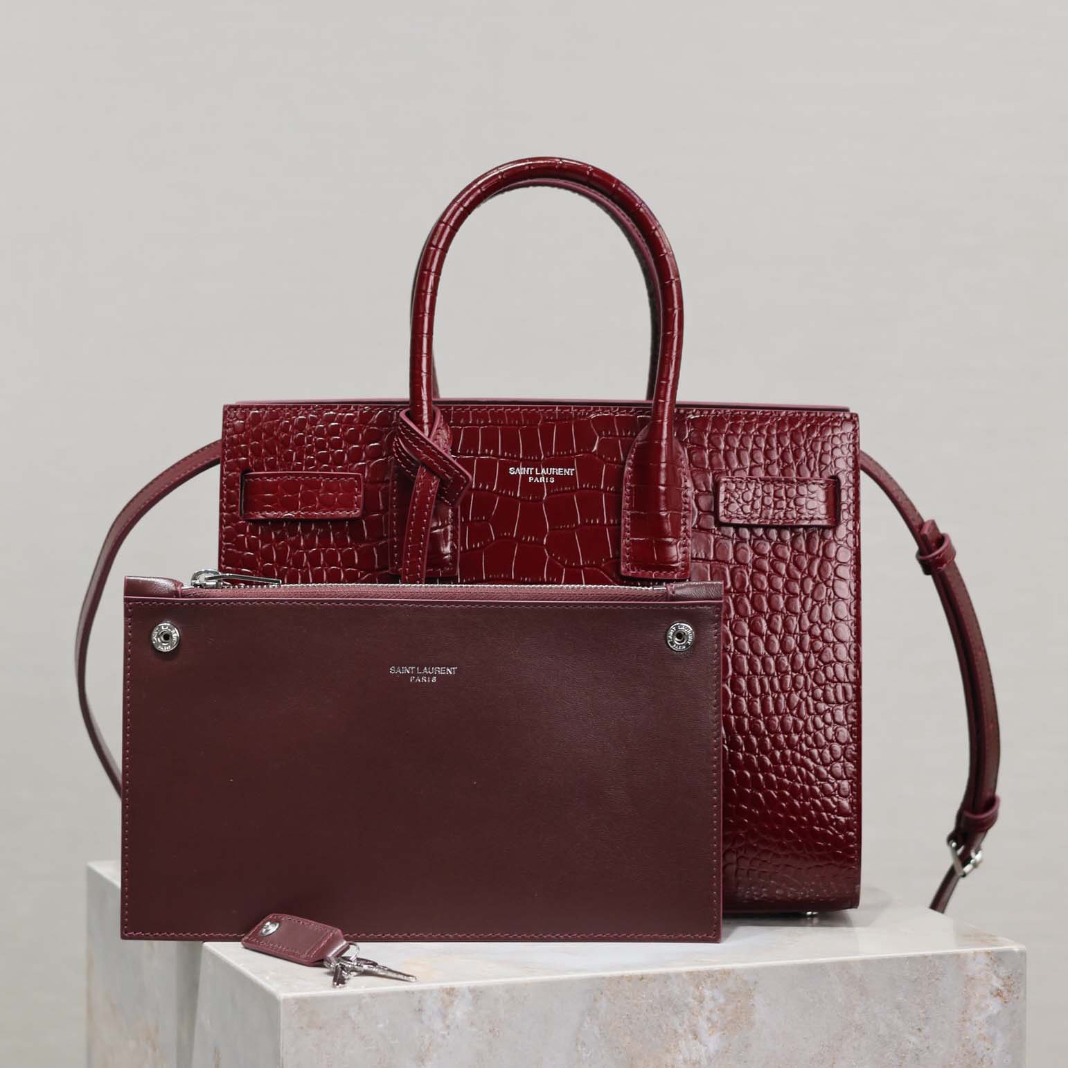 Close-up of gold YSL logo on maroon embossed crocodile leather bag