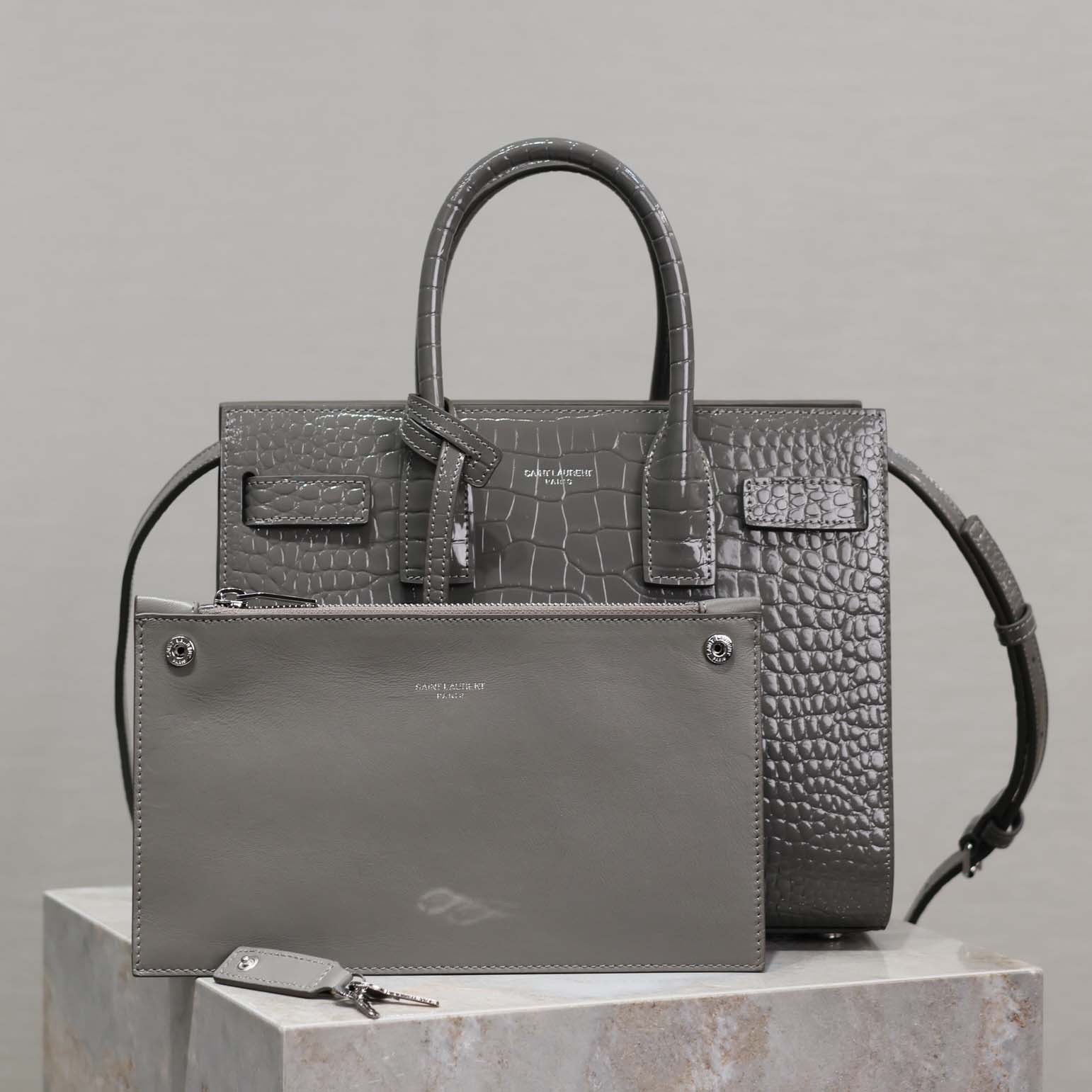 Close-up of baby silver YSL hardware on embossed crocodile leather bag